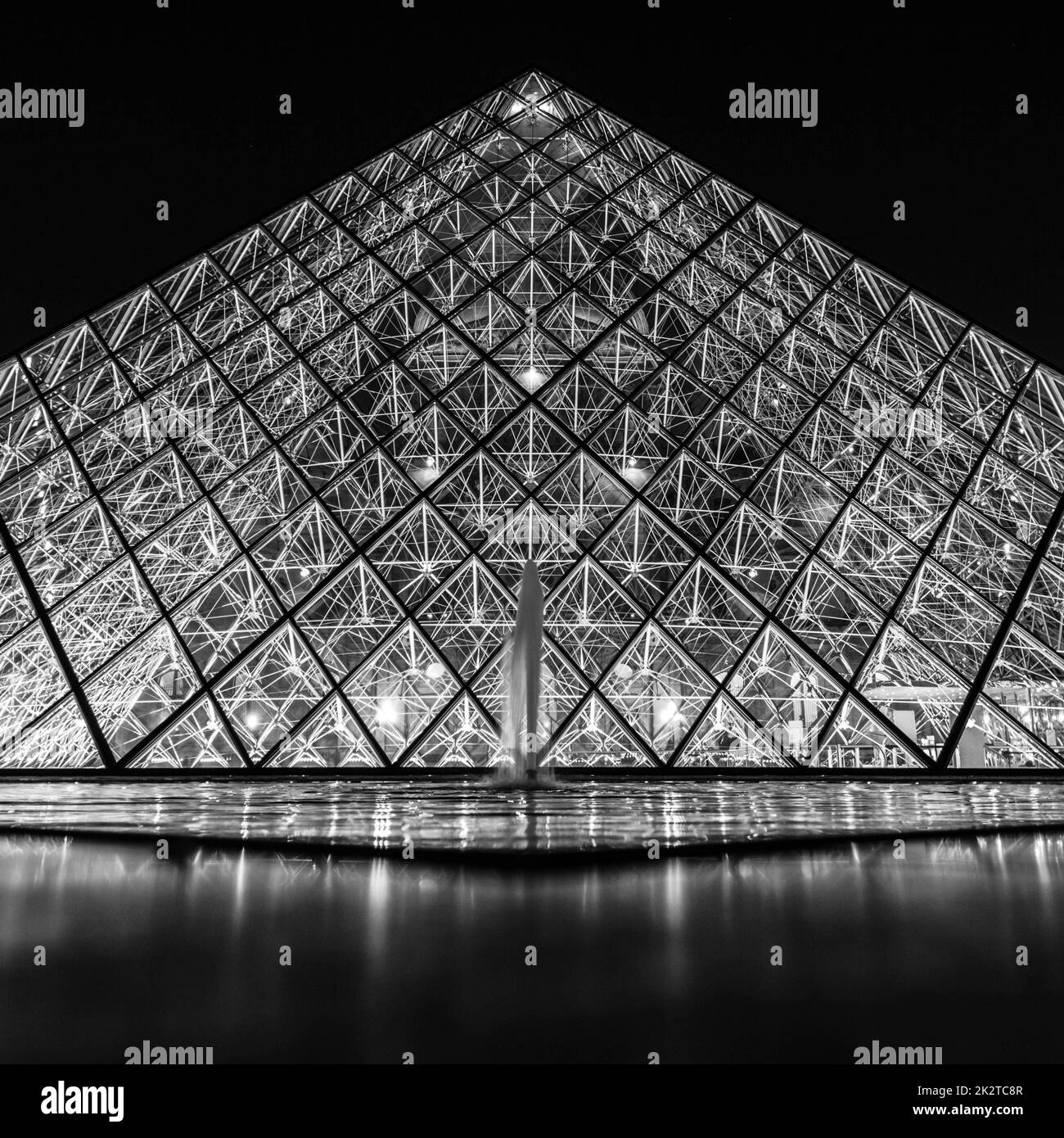 A grayscale shot of the Louvre Pyramid and fountain, close up Stock Photo