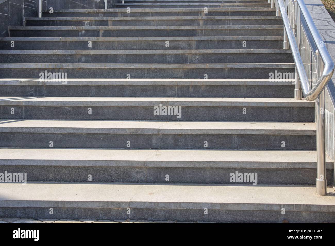 Outdoor concrete steps on a modern city staircase with metal railings on a sunny day, outdoors, bottom view Stock Photo