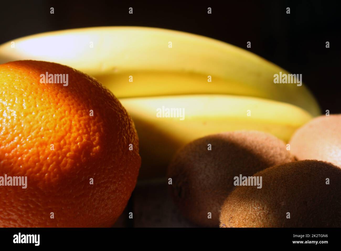 Kiwi, bananas, orange under the falling light from the window on a