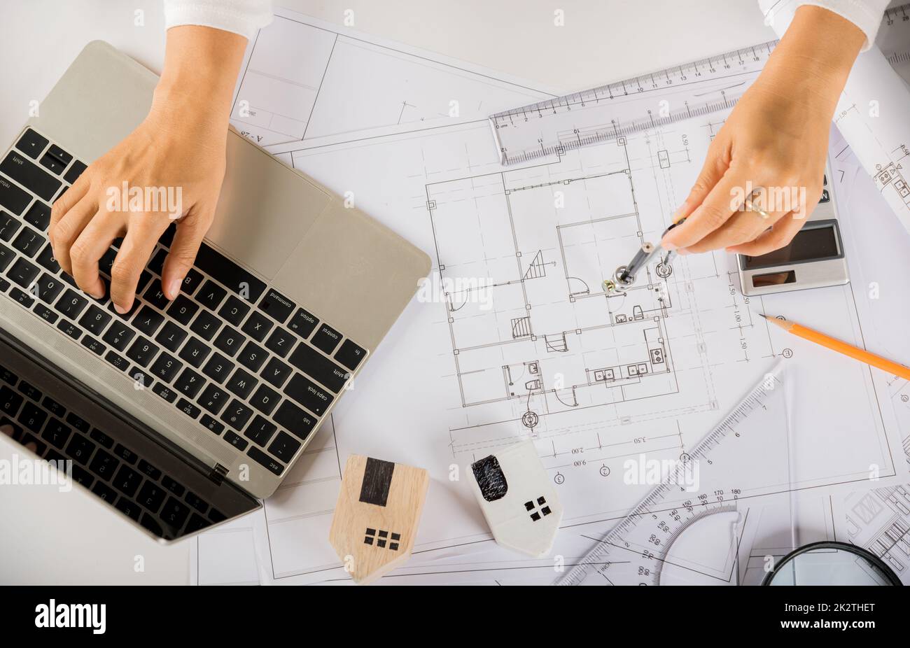 Architect typing laptop keyboard to review design of house before editing with compass Stock Photo