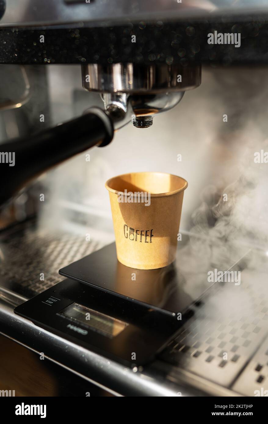 Disposable paper cup, coffee preparation, cooking process, hot steam. Barista work. The concept of cooking coffee, coffee to go. Stock Photo