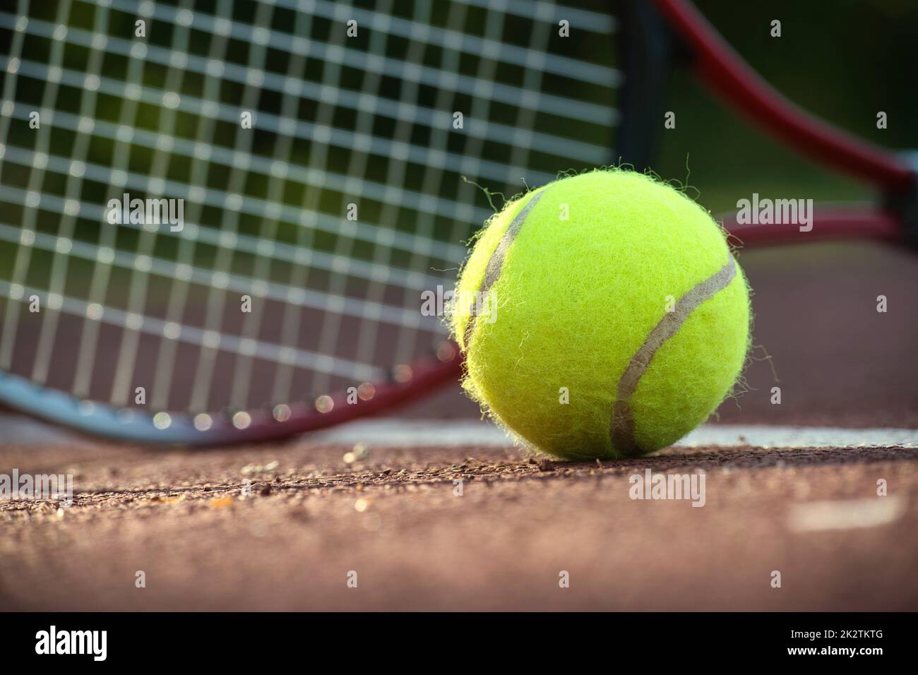 Yellow tennis ball near racquet and white line Stock Photo