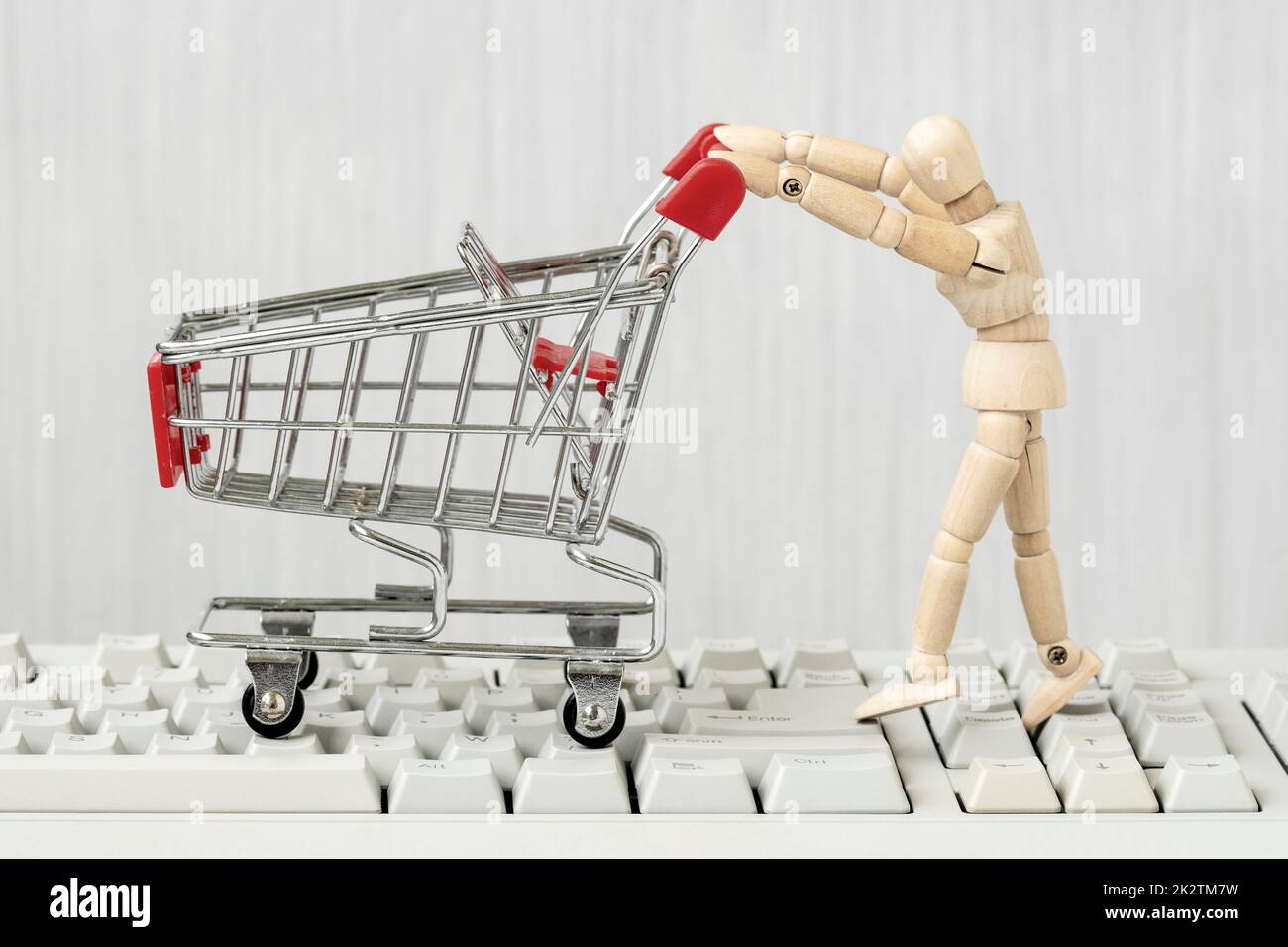 Wooden mannequin with shopping cart on computer keyboard Stock Photo