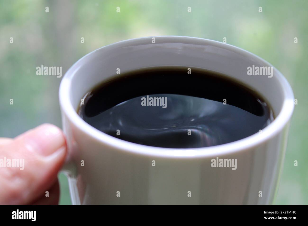 White mug with black coffee in hand close-up Stock Photo