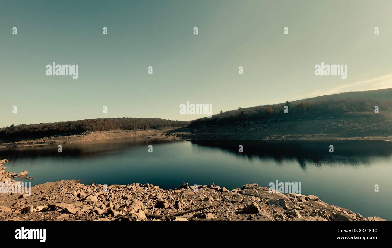 A scenic view of a calm reflective lake under the clear sky Stock Photo ...