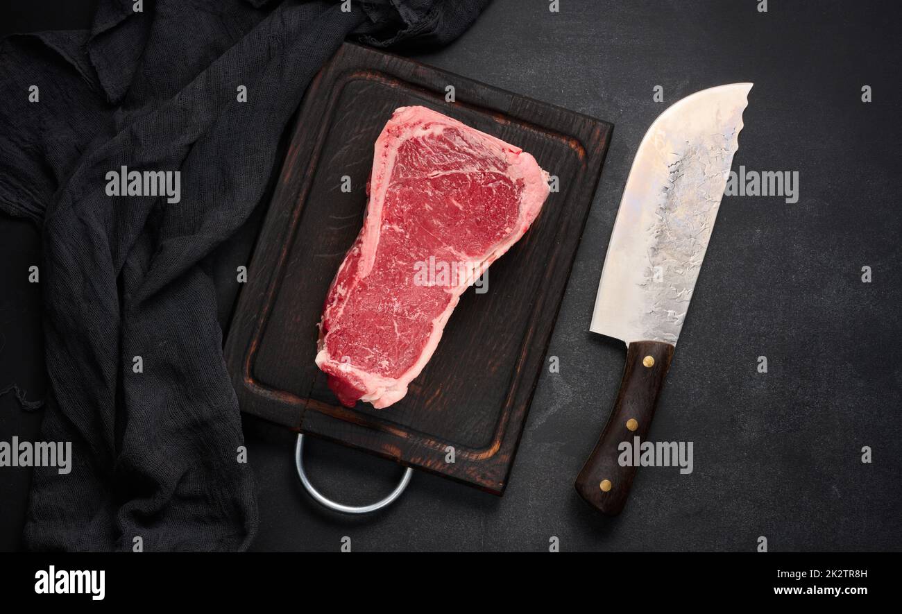 Fresh raw piece of beef meat, striploin steak on a black background, top view. Marbled piece of meat Stock Photo
