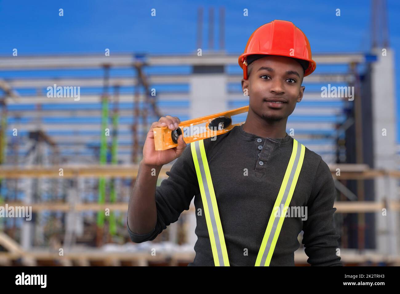 construction site worker holding level tool and wearing red security hat helmet safety equipment Stock Photo