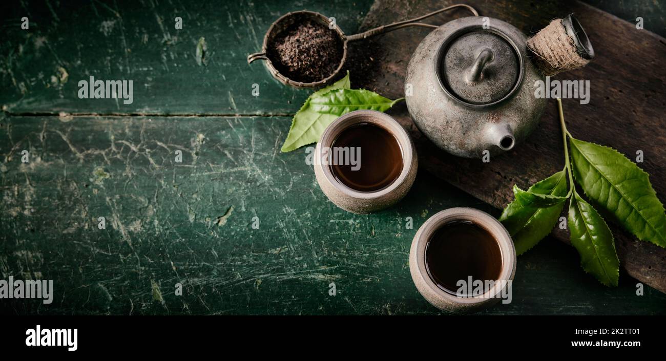 Vintage green asian tea pot with two mugs on rustic background. Stock Photo