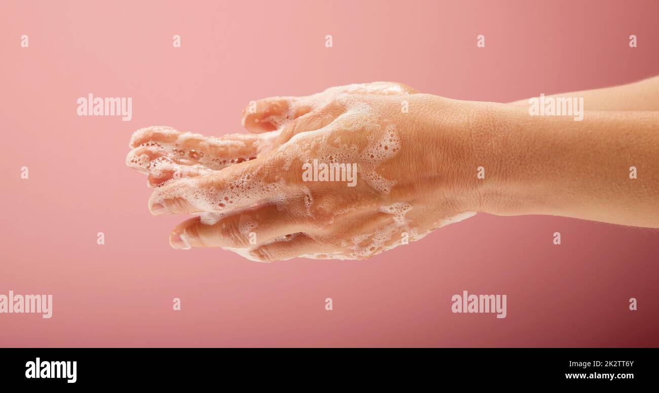 Woman s hands washing with soap, foam and water on bright pink