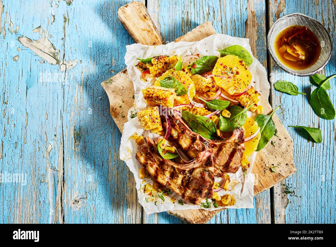 Tasty grilled lamb chops with corn served on table Stock Photo