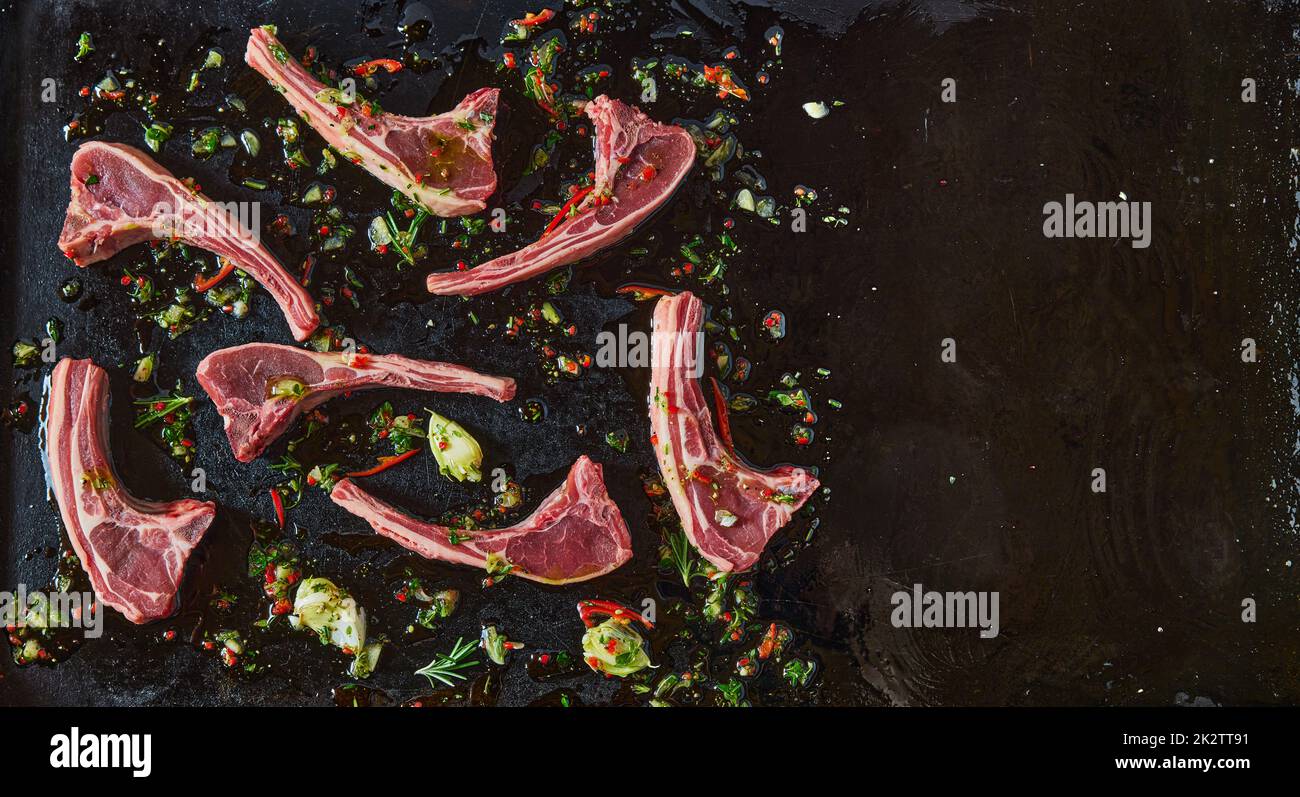 Top view of uncooked lamb chops with chili pepper on black background