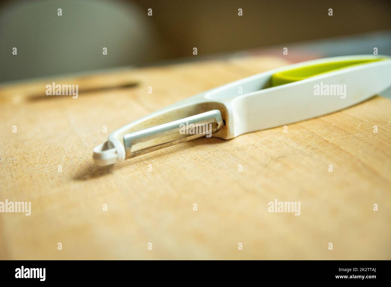 A kitchen tool for peeling vegetables is lying on a wooden board Stock Photo
