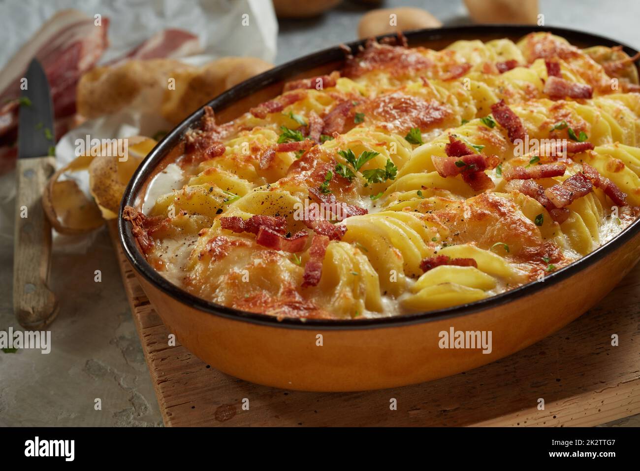 Delicious cheesy potato gratin in casserole pan on table Stock Photo