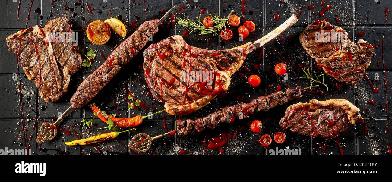 Grilled steaks covered with tomato sauce placed on table Stock Photo