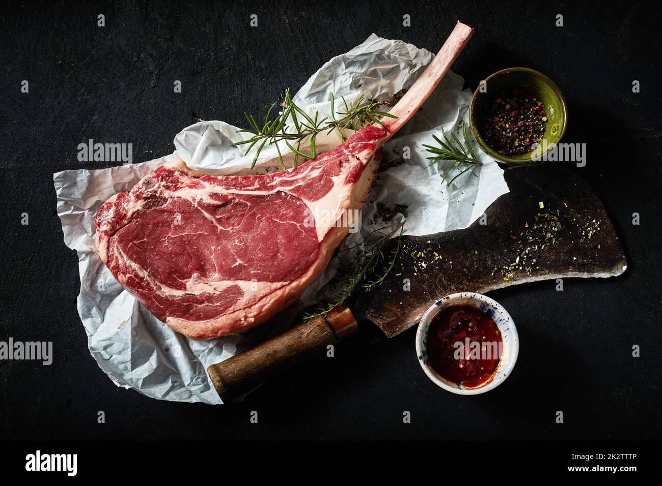 Raw tomahawk steak with spices and rosemary sprig Stock Photo