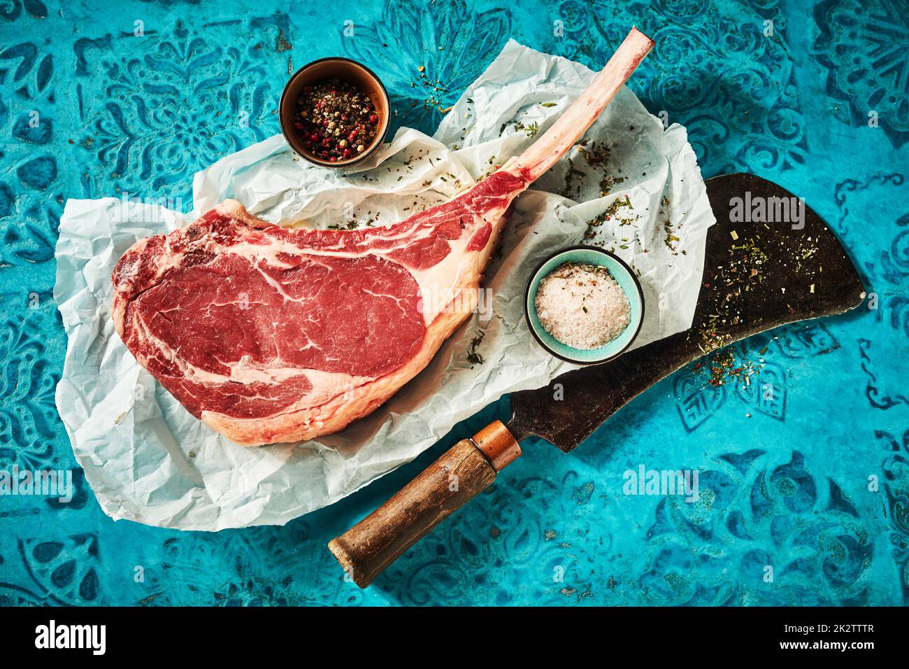 Raw tomahawk steak with spices and salt on paper Stock Photo