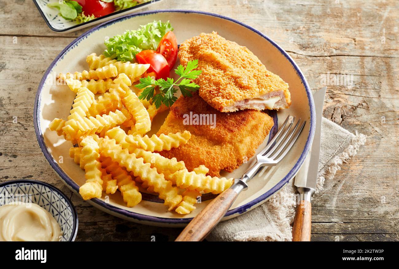 Schnitzel cordon bleu and crinkle fries on table Stock Photo - Alamy