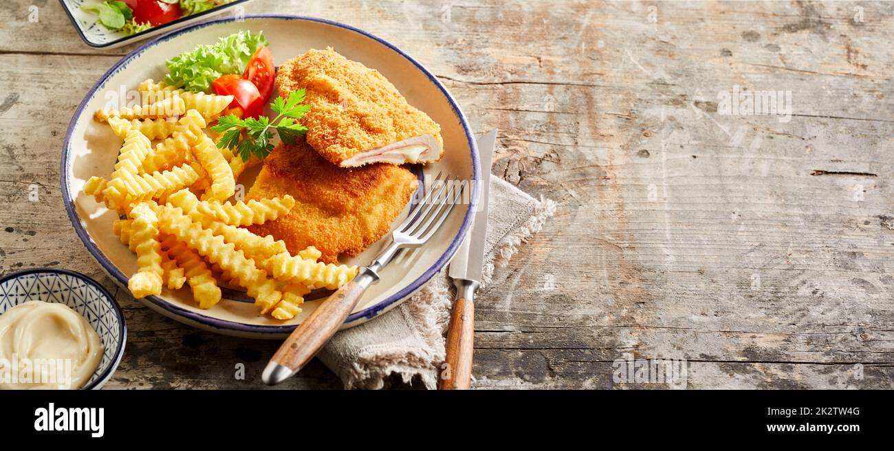 Appetizing cordon bleu and crinkle fries on plate Stock Photo