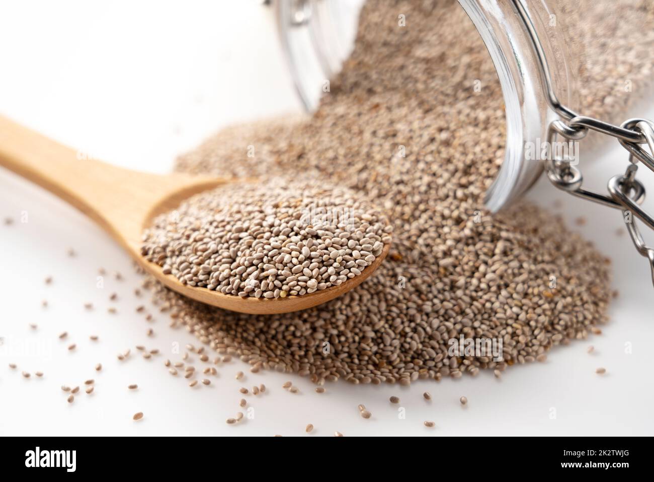 Wooden spoon, white chia seeds and glass container placed on white ...