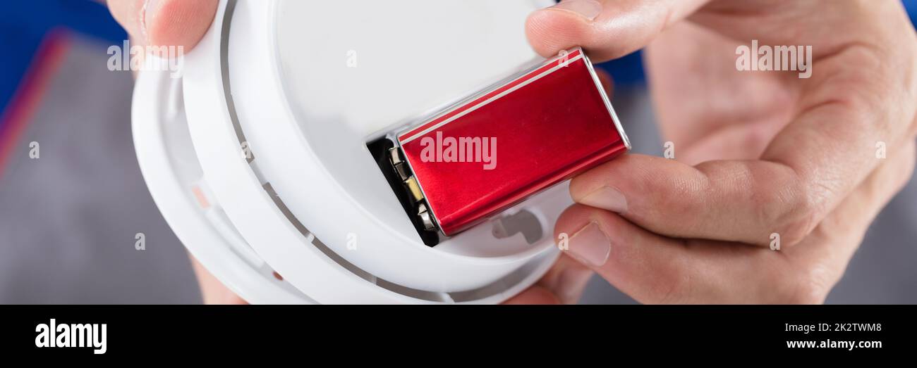 Person's Hand Inserting Battery In Smoke Detector Stock Photo