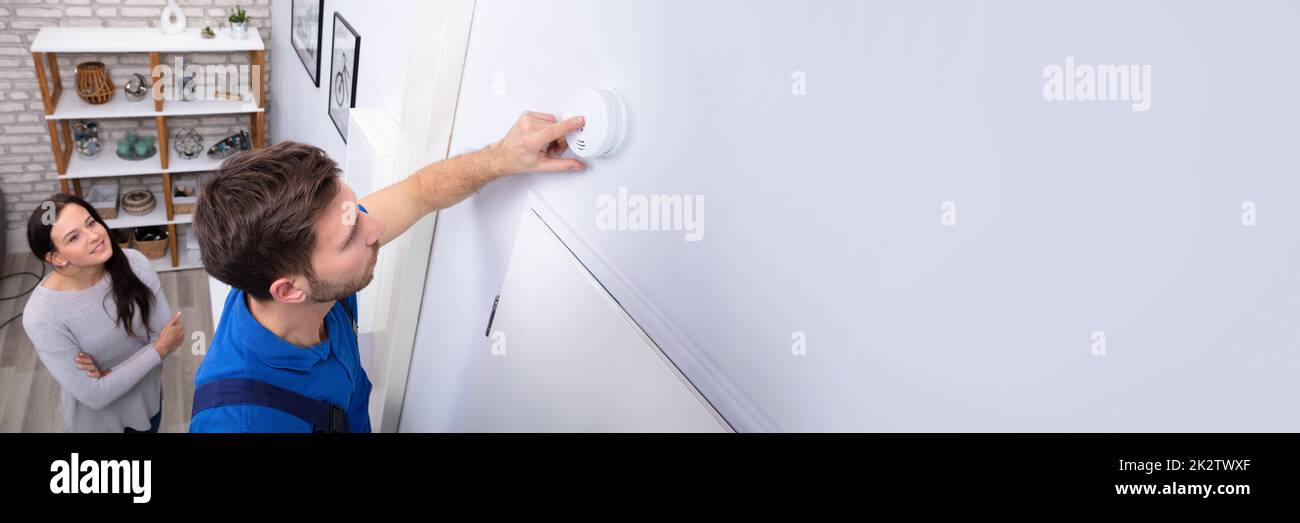 Repairman Installing Smoke Detector On Wall Stock Photo