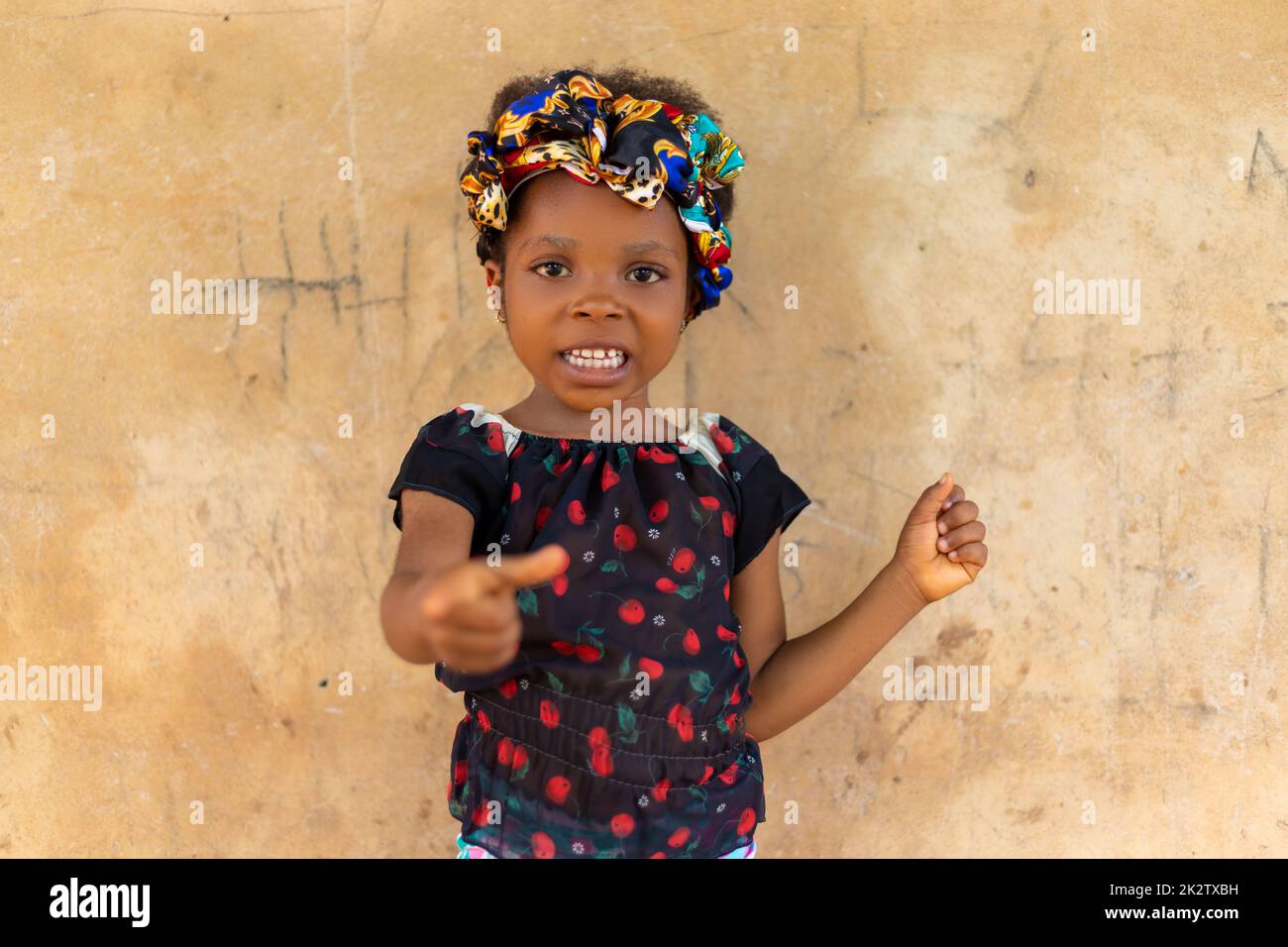 An adorable Nigerian kid with colorful headband smiling and pointing at the  camera Stock Photo - Alamy