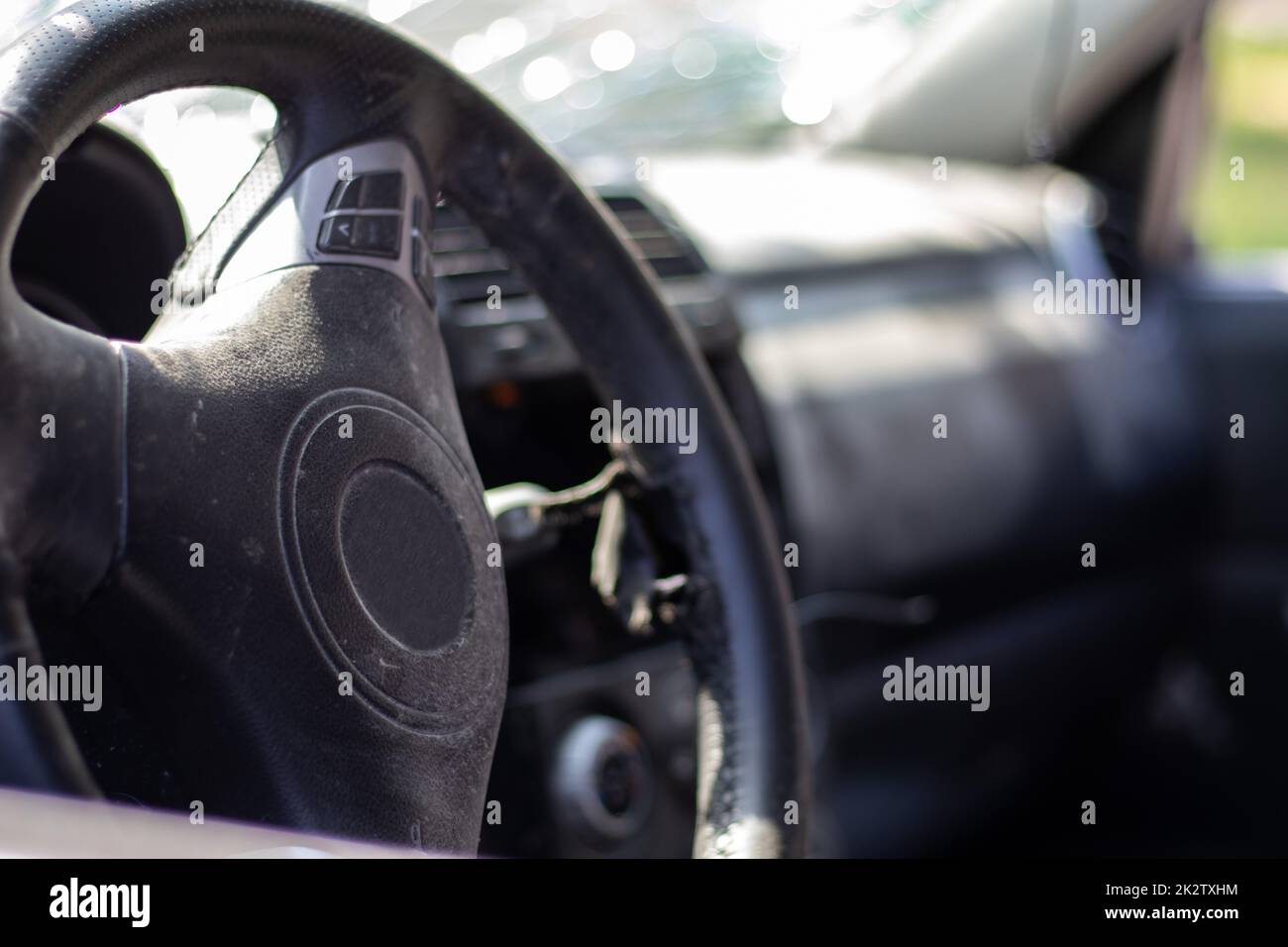 Close-up of the steering wheel of a car after an accident. The driver's airbags did not deploy. Soft focus. Broken windshield with steering wheel. Vehicle interior. Black dashboard and steering wheel. Stock Photo