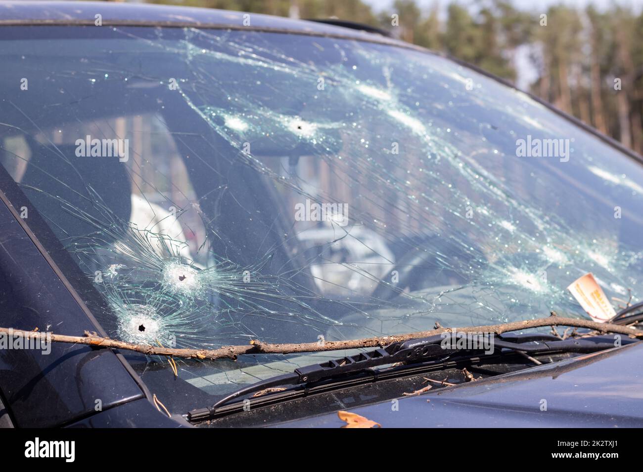 Holes on the windshield of the car, it was shot from a firearm. Bullet holes. Smash car