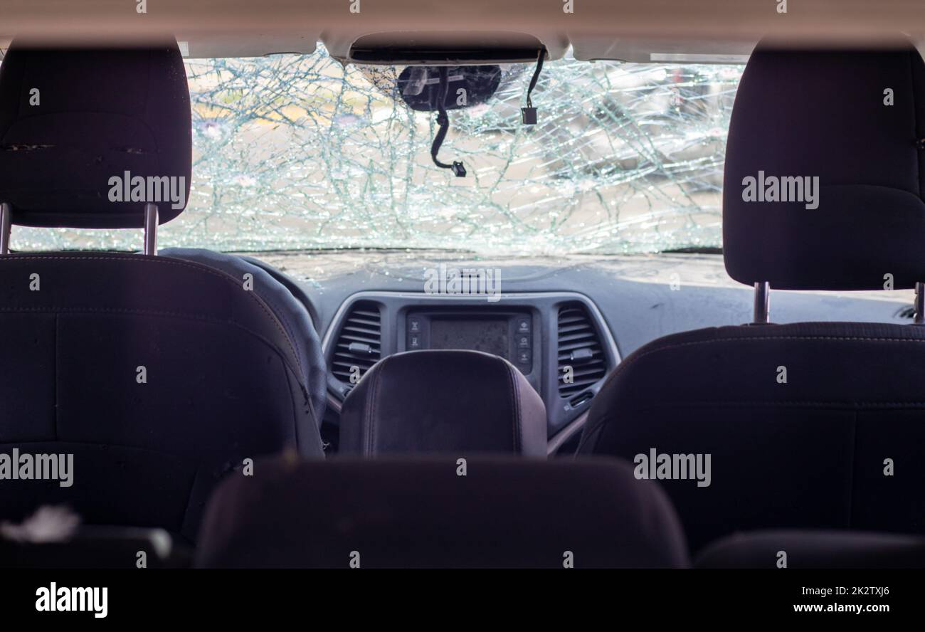 Damaged car window after an accident. Broken windshield as a result of an accident, inside view. Cabin interior details, view from the cab. Safe movement. Broken windshield. Glass crack and damage. Stock Photo