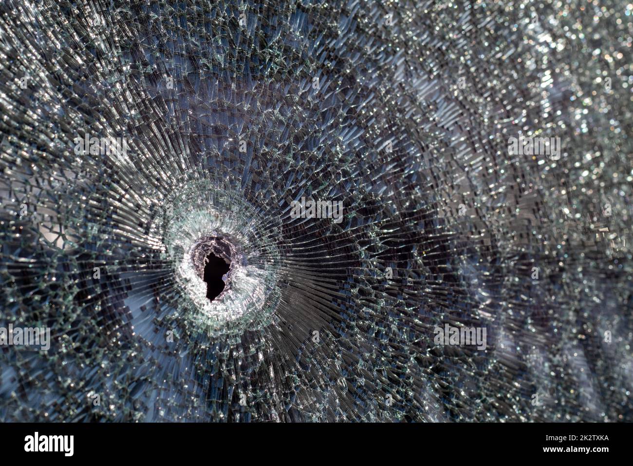 Holes on the windshield of the car, it was shot from a firearm. Bullet holes. Smash car windshield, broken and damaged car. The bullet made a cracked hole in the glass. Stock Photo