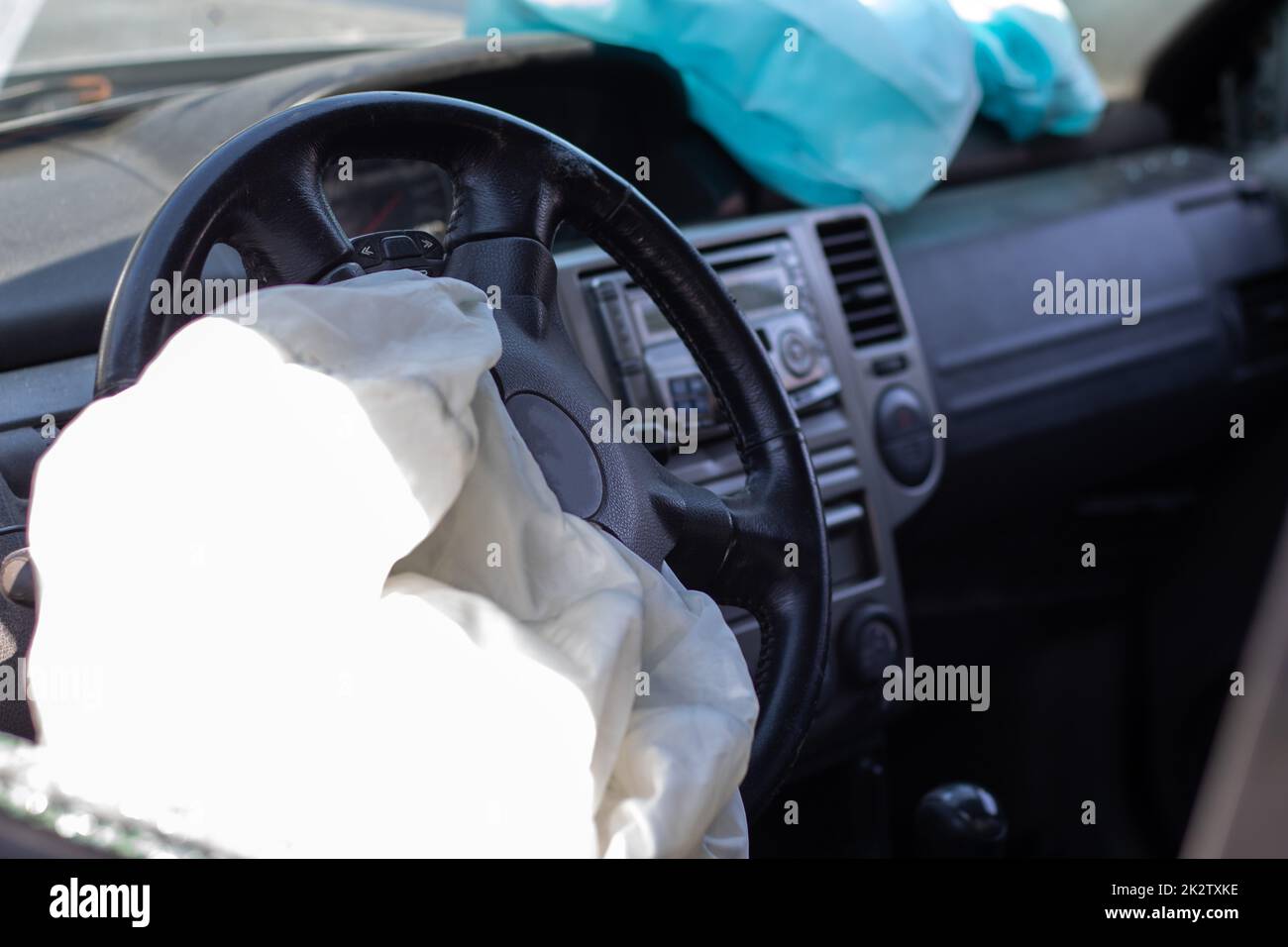 The driver's airbag deployed on the steering wheel of the car after the collision. Deflated airbags after flared deployment. The airbag deployed. Car after an accident. Safety device in the car. Stock Photo