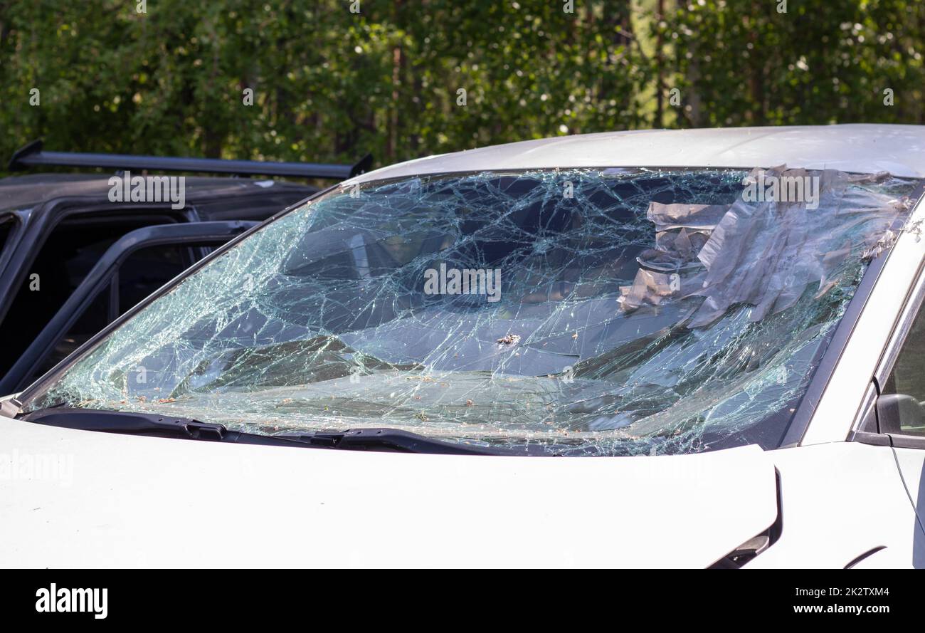 Close-up of a car with a broken windshield after a fatal crash. Consequence of a fatal car accident. Automobile danger. Reckless dangerous driving. Vehicle after an accident with a pedestrian. Stock Photo