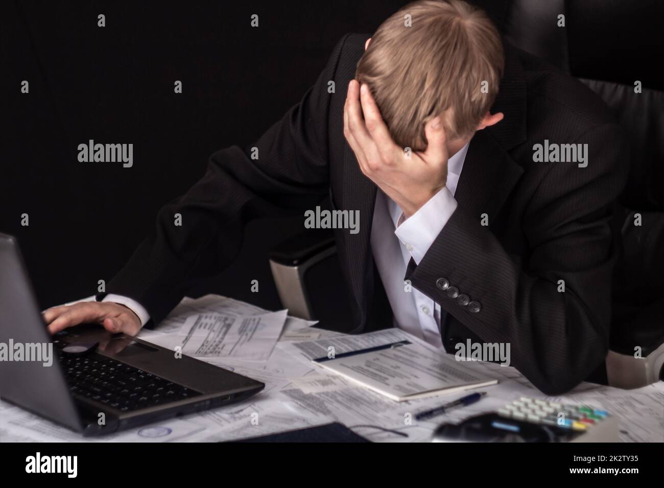 Businessman signing a contract. The Manager makes the report and fills in the Declaration. Businessman at work in his workplace. Young guy at the table with a laptop, cash register documents. Stock Photo