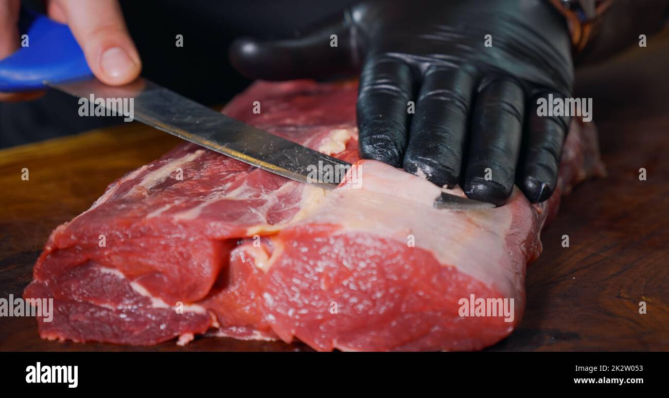 Cutting Portions of Fresh Raw Beef Meat As Preparation Before Cooking. Juicy Fresh Meat. Stock Photo