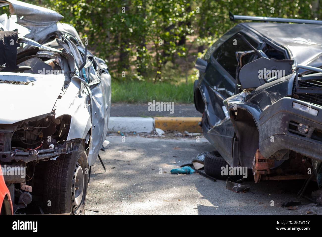 Many broken cars after a traffic accident in the parking lot of a restoration service station on the street. Car body damage workshop outdoors. Sale of insurance emergency vehicles at auction. Stock Photo