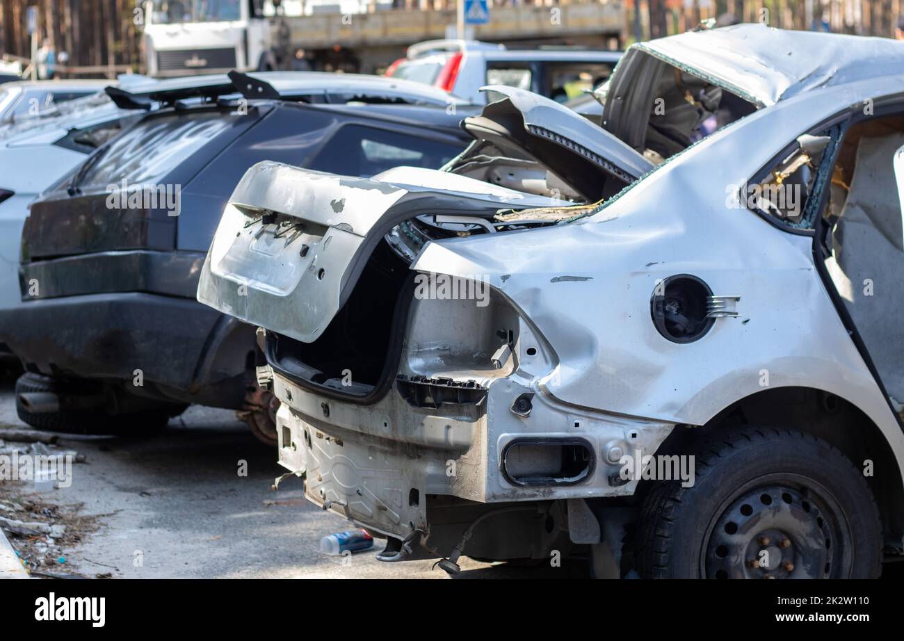 Many broken cars after a traffic accident in the parking lot of a restoration service station on the street. Car body damage workshop outdoors. Sale of insurance emergency vehicles at auction. Stock Photo