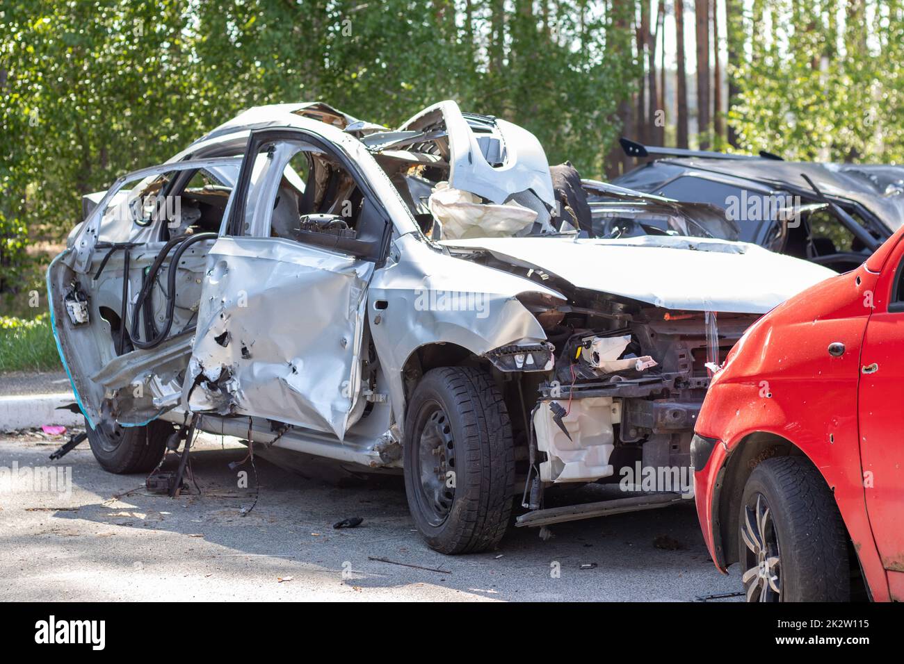 Many broken cars after a traffic accident in the parking lot of a restoration service station on the street. Car body damage workshop outdoors. Sale of insurance emergency vehicles at auction. Stock Photo