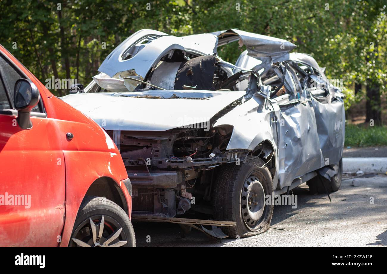 Many broken cars after a traffic accident in the parking lot of a restoration service station on the street. Car body damage workshop outdoors. Sale of insurance emergency vehicles at auction. Stock Photo
