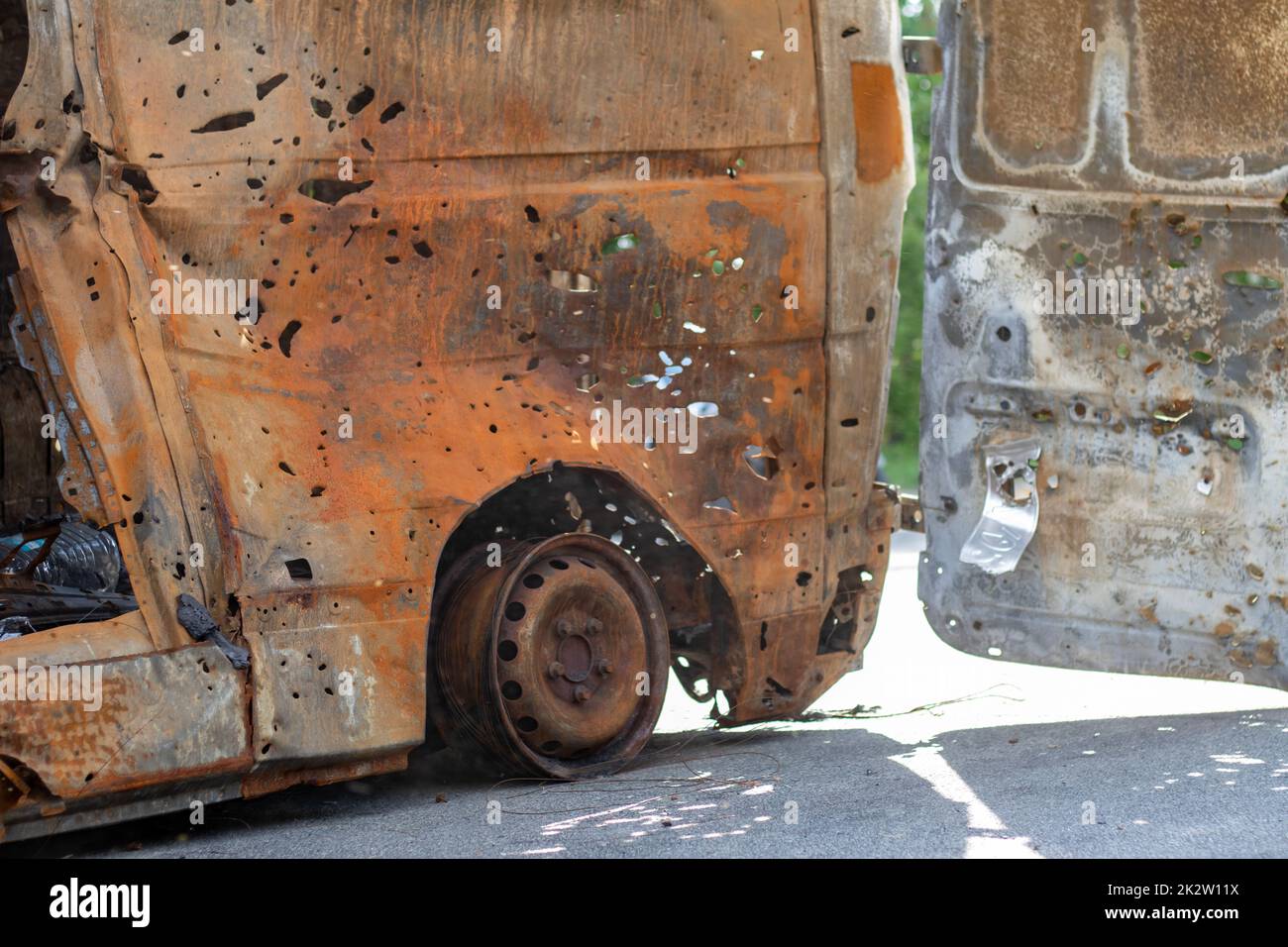 Burnt car body riddled with bullets. Russia's war against Ukraine. Shot by the Russian military car of civilians during the evacuation. Traces of bullets and fragments of shells. Stock Photo