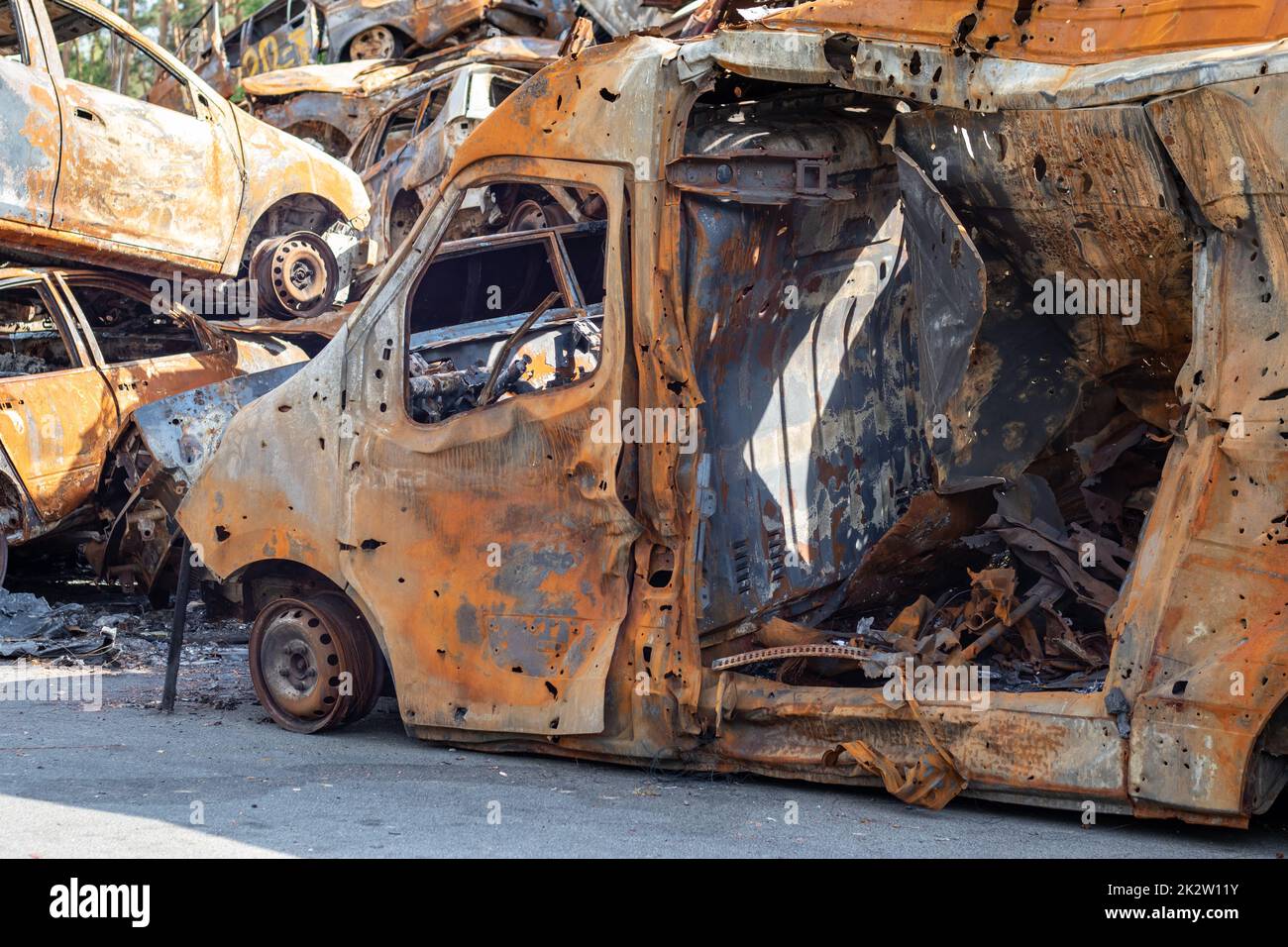 Cars after the fire. Iron parts of a burnt car. Burnt-out cars abandoned on the side of a quiet countryside. Explosion, the result of a fire. Car insurance concept. War of Russia against Ukraine. Stock Photo