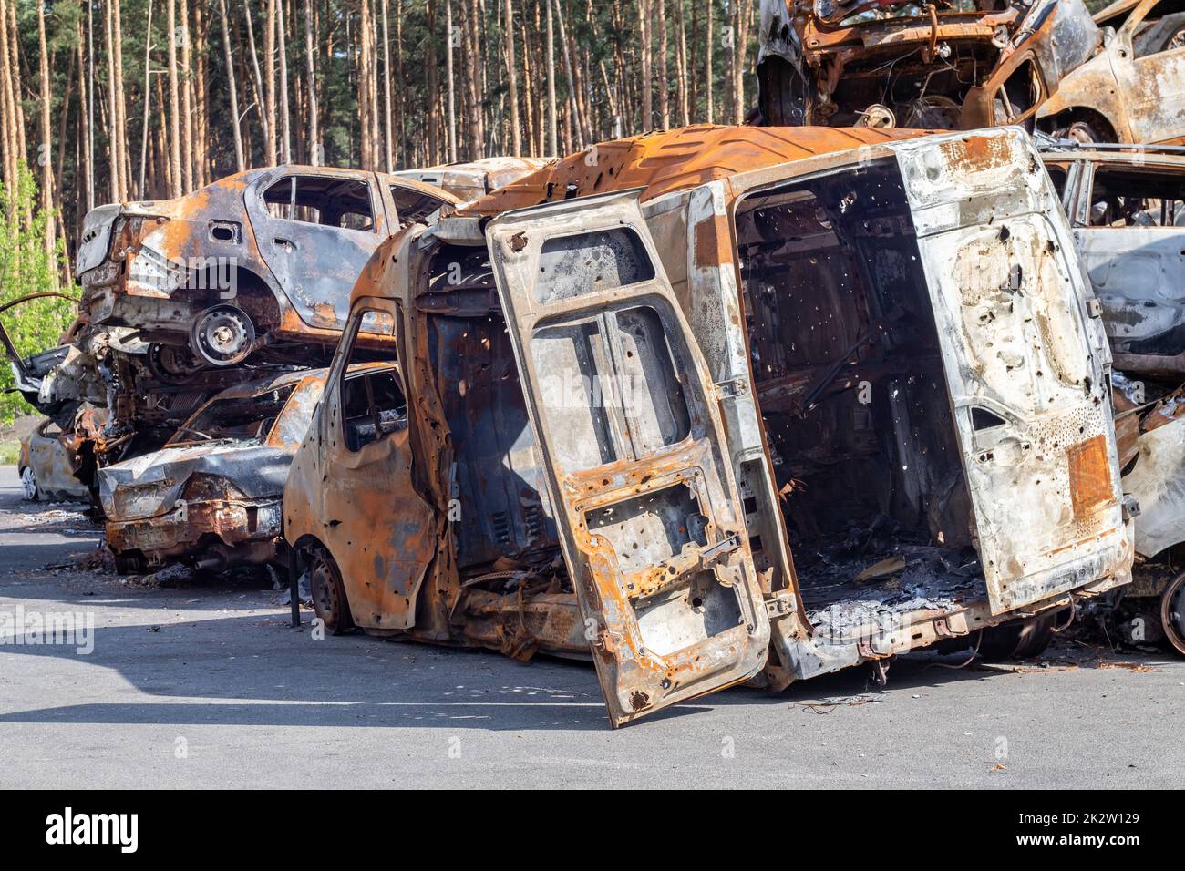 Cars after the fire. Iron parts of a burnt car. Burnt-out cars abandoned on the side of a quiet countryside. Explosion, the result of a fire. Car insurance concept. War of Russia against Ukraine. Stock Photo