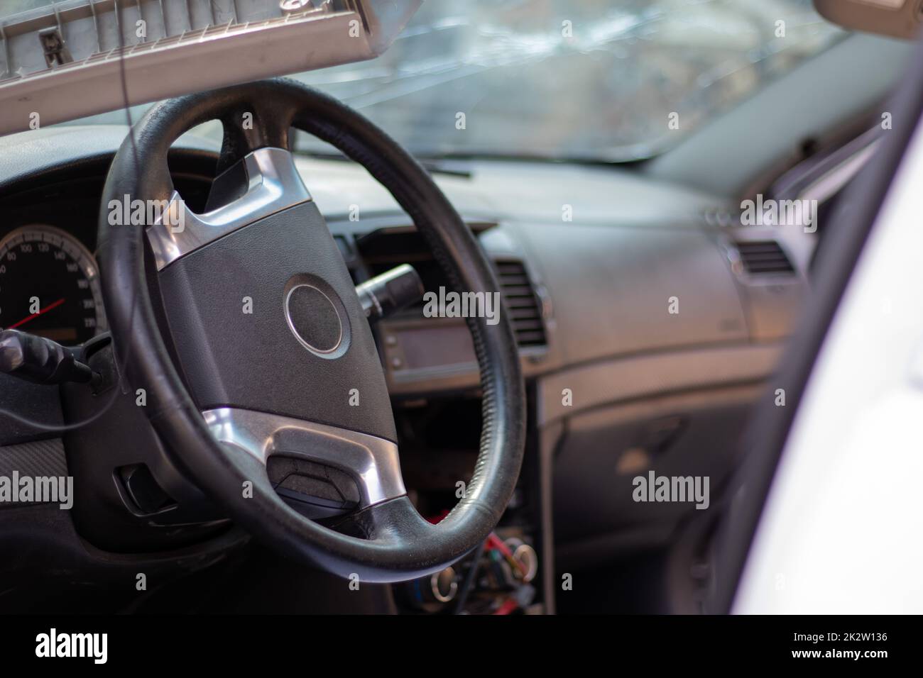 Close-up of the steering wheel of a car after an accident. The driver's airbags did not deploy. Soft focus. Broken windshield with steering wheel. Vehicle interior. Black dashboard and steering wheel. Stock Photo