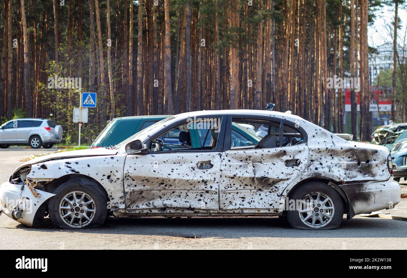 Shot, damaged cars during the war in Ukraine. The vehicle of civilians affected by the hands of the Russian military. Shrapnel and bullet holes in the body of the car. War of Russia against Ukraine. Stock Photo
