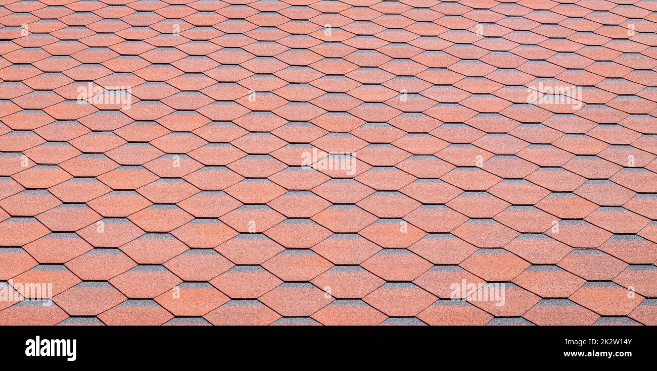 New roof with red shingles. Tiles on the roof of the house. Use to advertise roof fabrication and maintenance. Spotted texture. Affordable roofing. High quality photo with copy space. Stock Photo