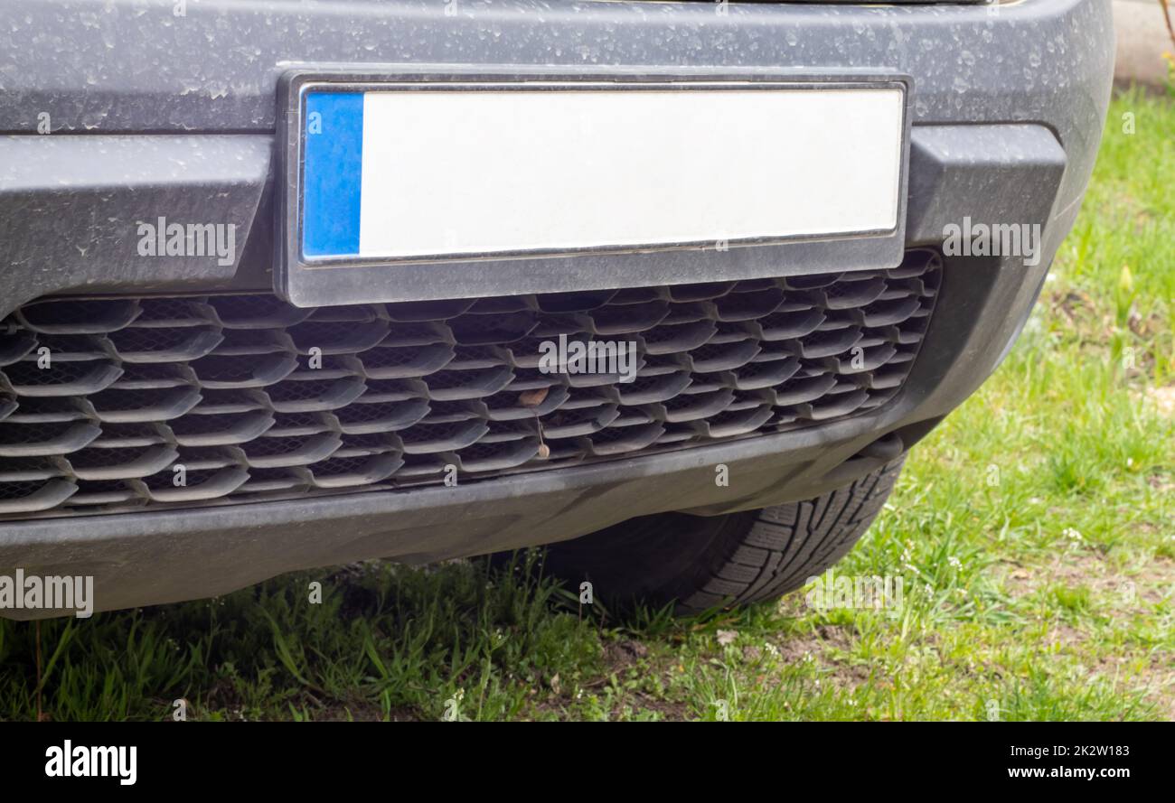 Car number without letters and numbers on the car bumper. Blank white license plate in front of the car, all logos removed, close up. The front rectangular license plate of a vehicle on the street. Stock Photo