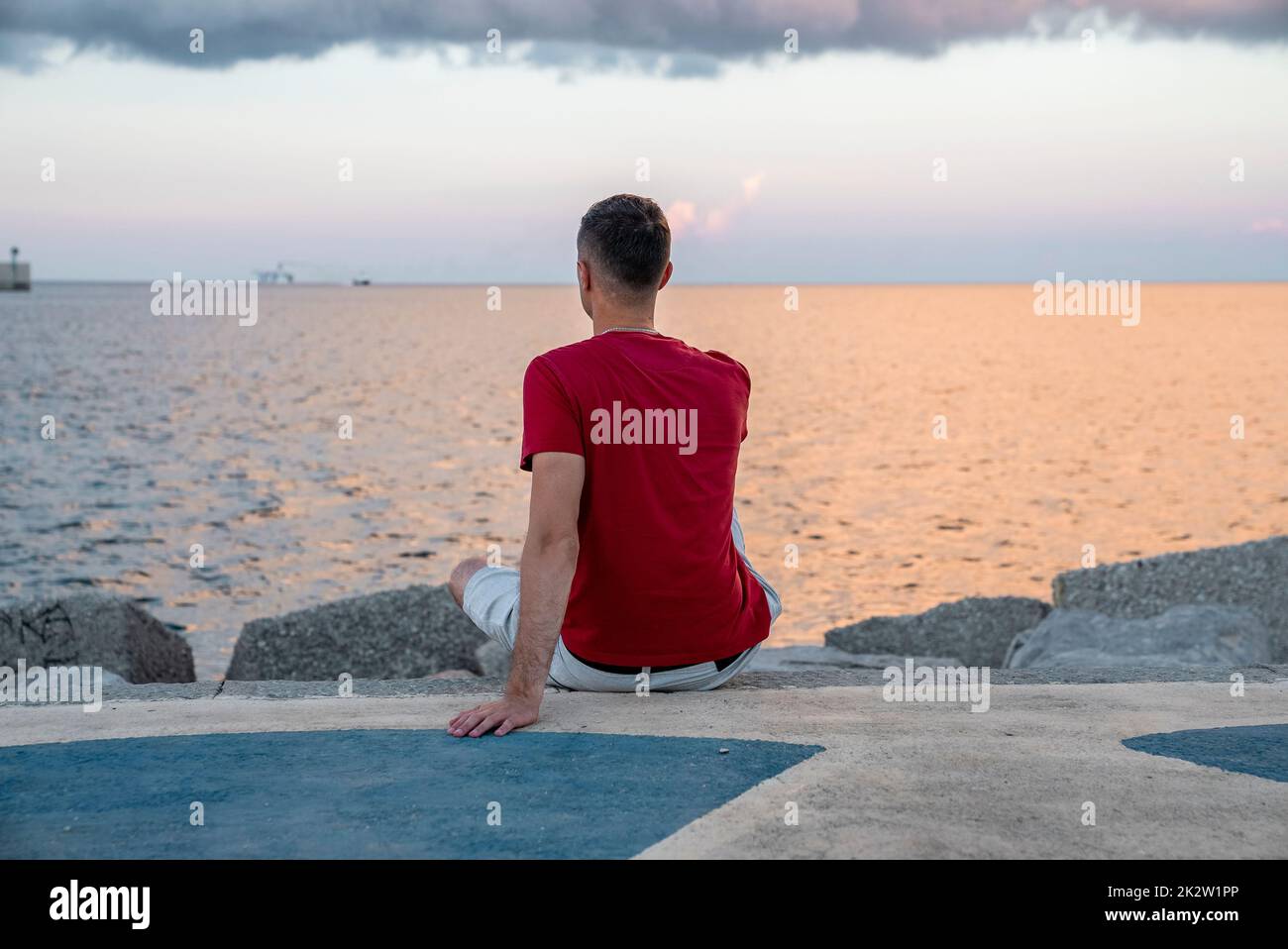 Rear view of tourist looking at beach while relaxing on promenade Stock Photo