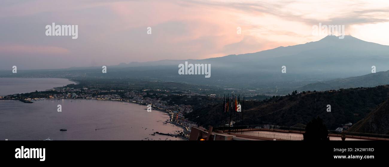 Picturesque scenery of Hotel Elios and Etna Volcano by seascape during sunset Stock Photo