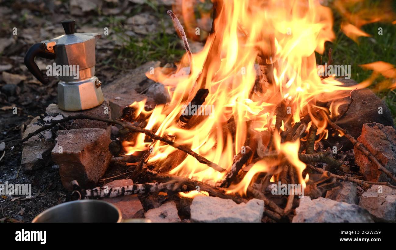 Bonfire burning in tourist camp in mountains. Beautiful campfire, burning wood in summer evening. Active lifestyle, traveling, hiking and camping concept. Campfire burning in slow motion Stock Photo