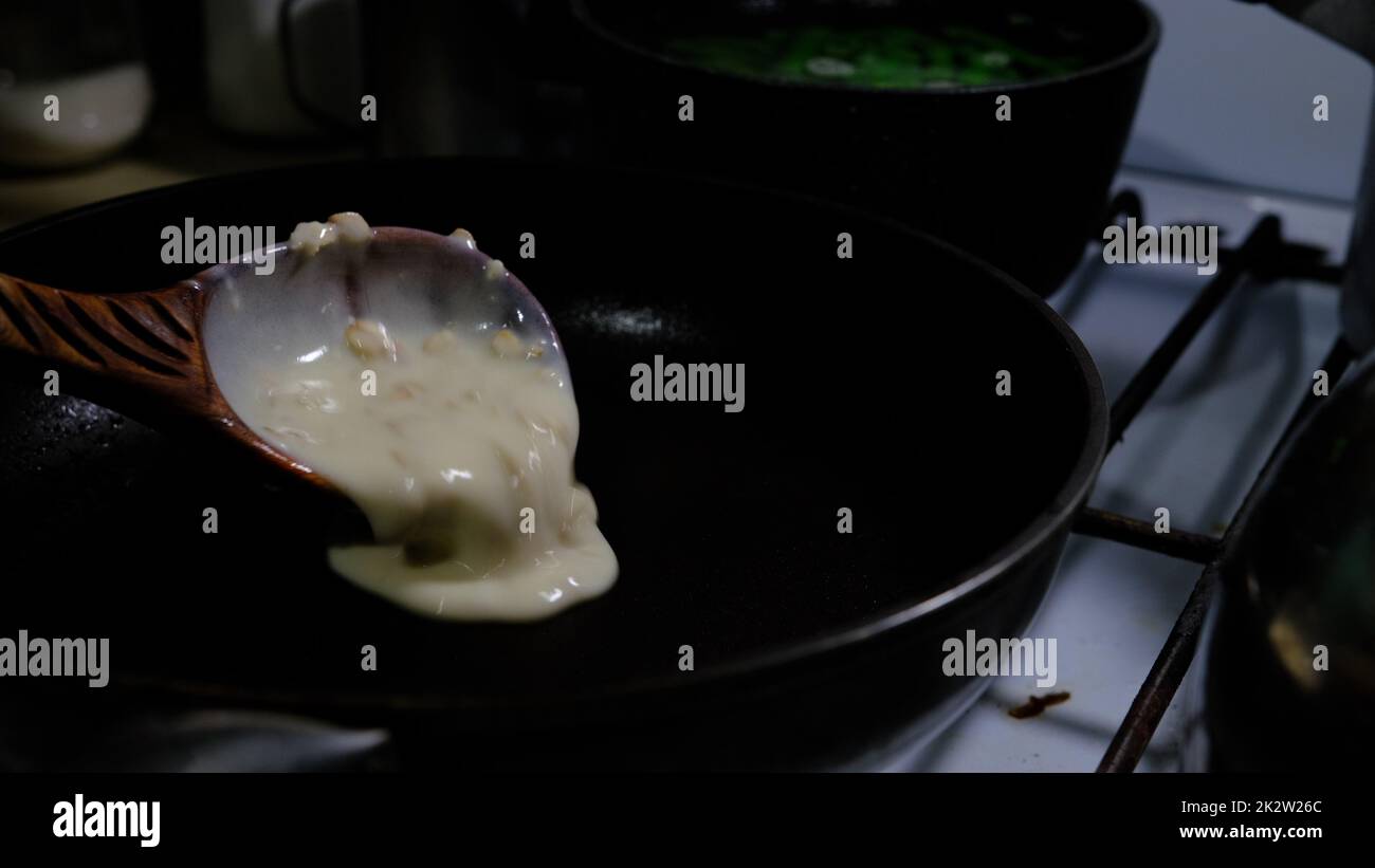 Filling a pan with pancake dough. Cooking on gascooker. Pancakes with