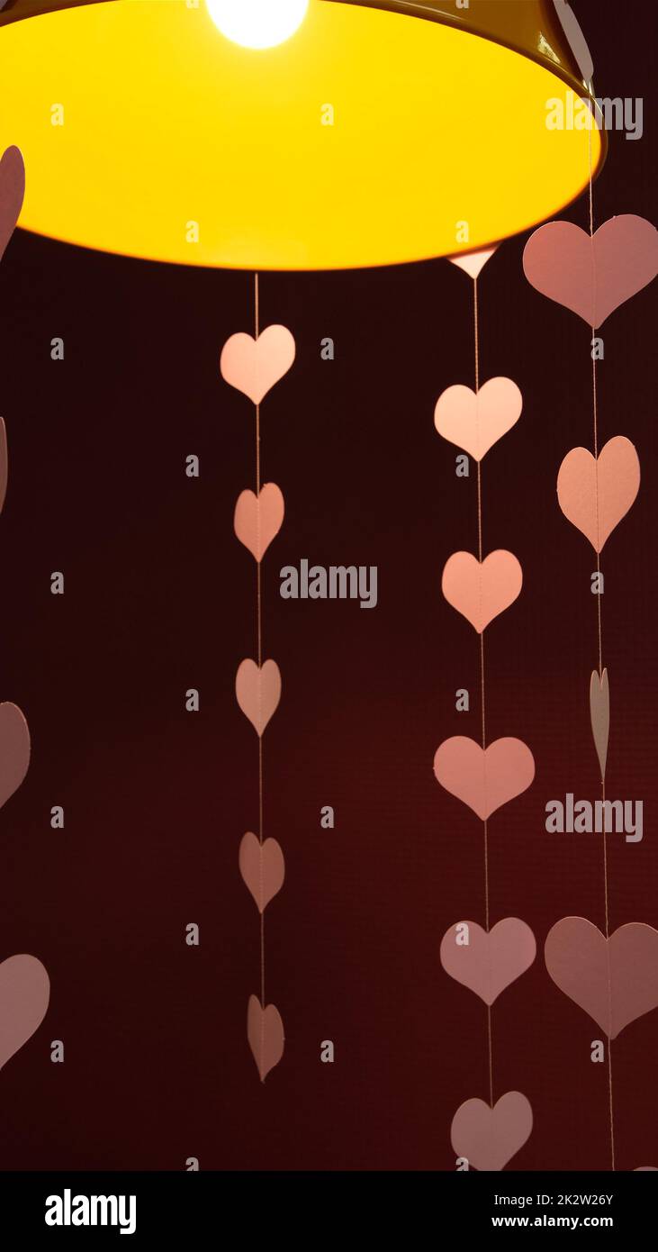 Flying red paper hearts on red dark background Symbol of love flying pink hearts Happy Valentines Day Hearts under Lamp Stock Photo